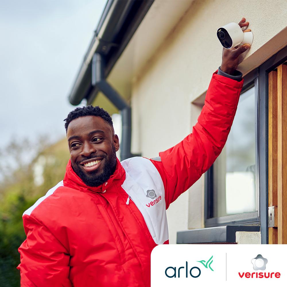 Un installateur Verisure vérifie la caméra de sécurité Arlo devant la maison d'un client
