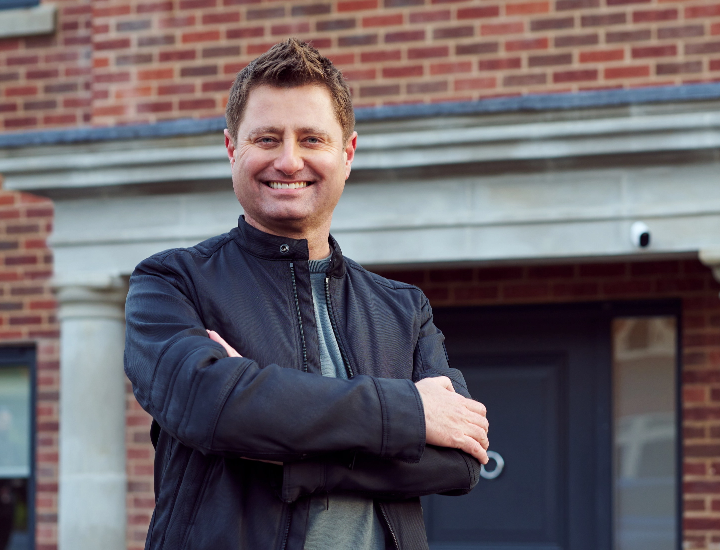 George Clarke, Influential architect on TV, stands outside a house with an Arlo security camera in the background