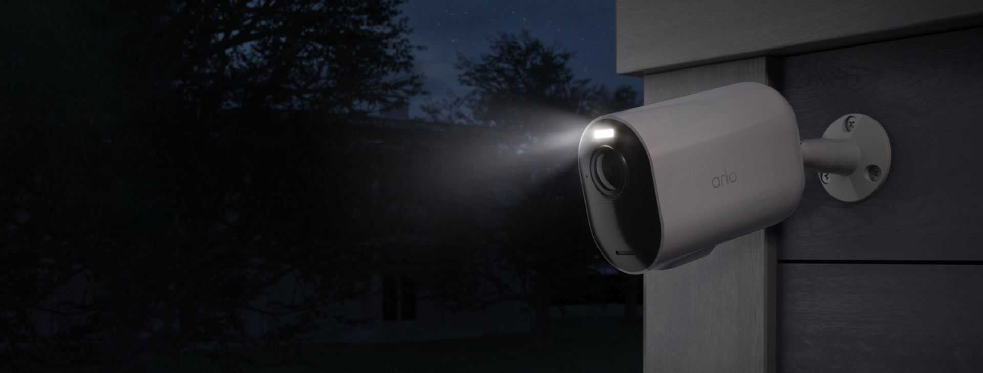 Die Arlo Ultra 2 XL Überwachungskamera, installiert an einer Wand bei Nacht mit eingeschaltetem Strahler.