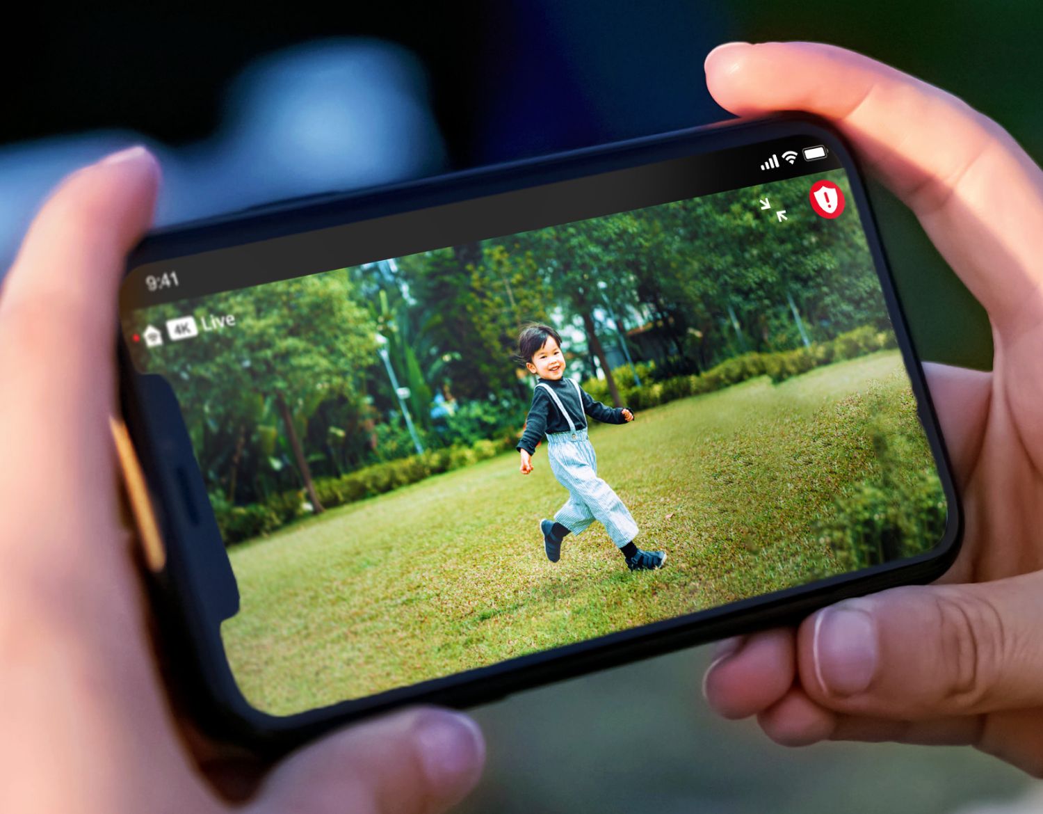 Eine Person sieht ein Bild eines Jungen im Garten aus seiner Arlo -Überwachungskamera auf seinem Handy aus