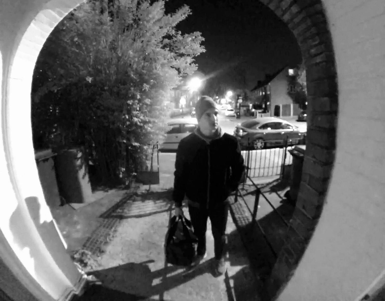 En bild från en Arlo trådlös videodörrklocka visar en man i mörka kläder vid ytterdörren