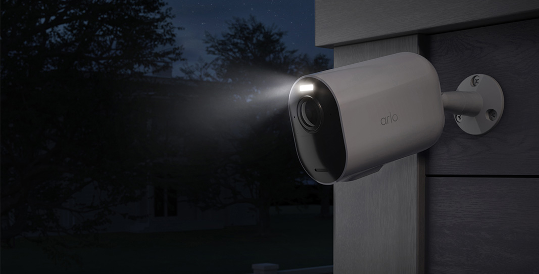 Övervakningskameran Arlo Ultra 2 XL installerad mot en vägg på natten med strålkastarljuset på.
