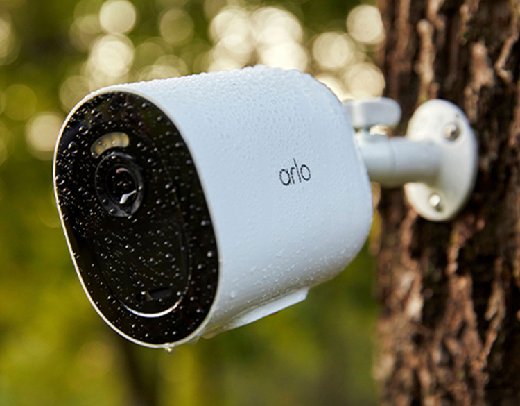 Arlo Go 2 beveiligingscamera hangend tegen een boom in de regen