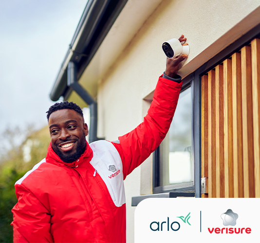 En Verisure-installatör kontrollerar Arlo-säkerhetskameran framför en kunds hem.