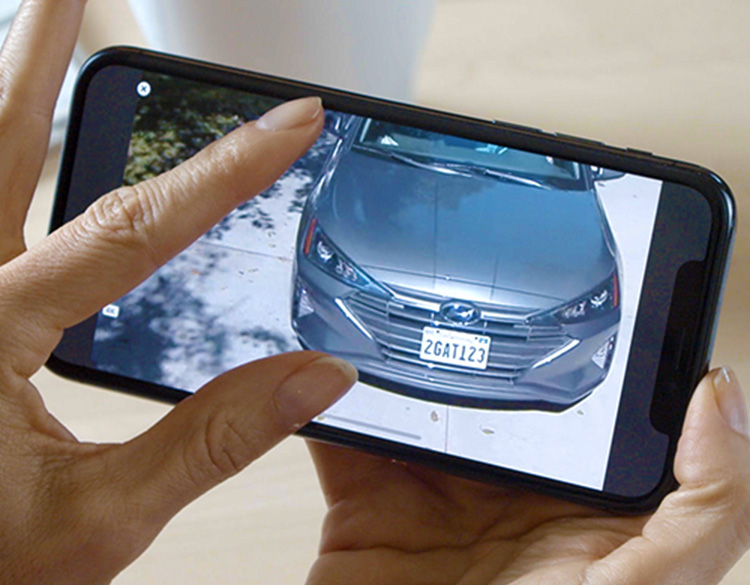 En person ser zoomer inn på et bilde av en bil fra Arlo sikkerhetskamera på mobiltelefonen