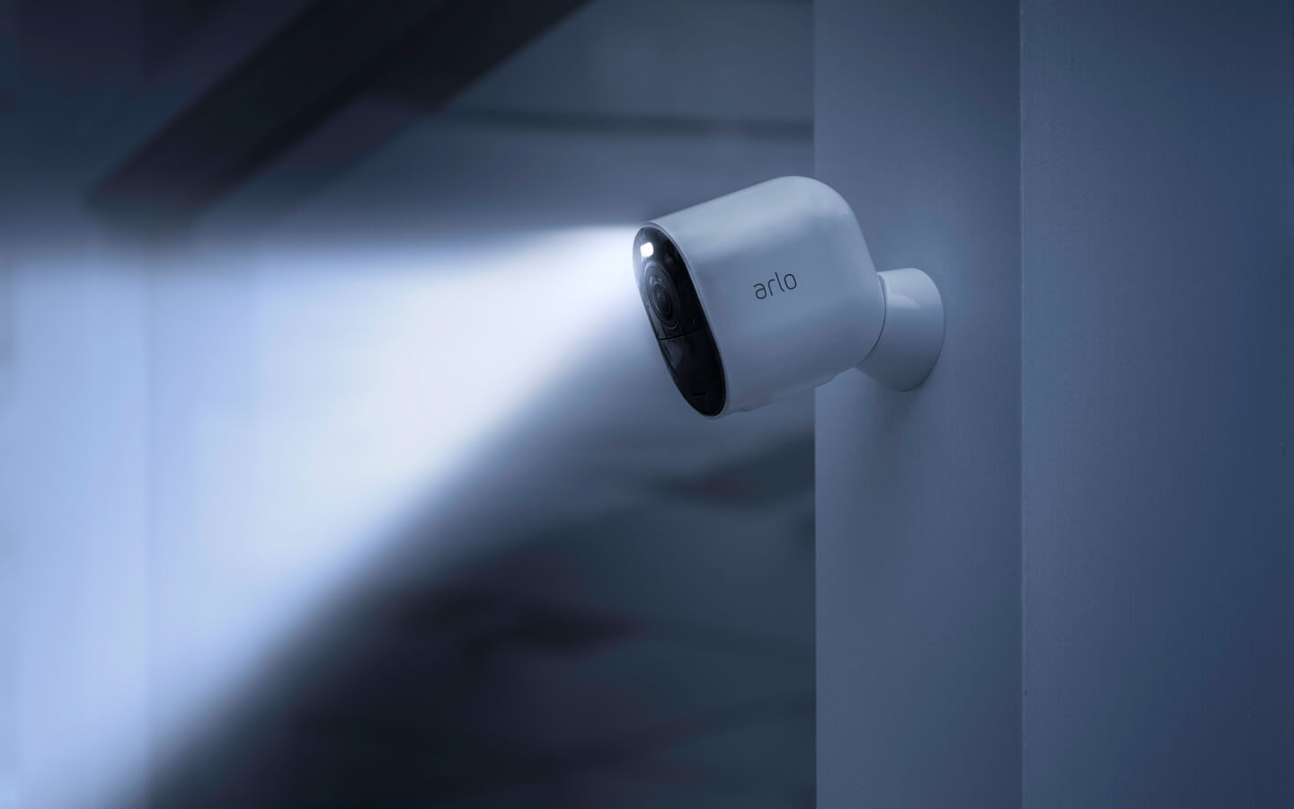 La caméra de sécurité Arlo Ultra 2 contre un mur avec le projecteur intégré qui illumine les alentours dans la nuit.