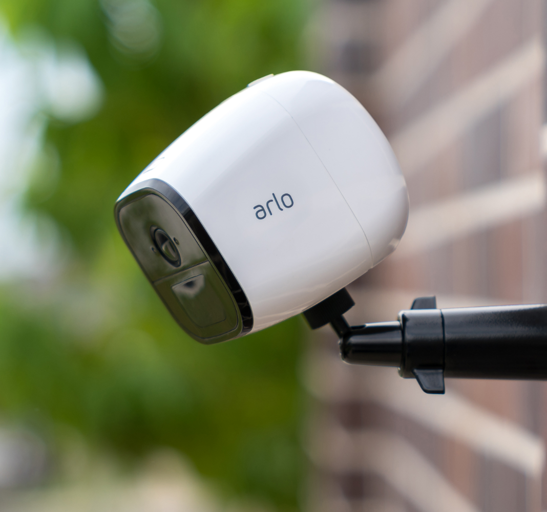 La caméra de sécurité extérieure 4G Arlo Go tenue par une perche et qui filme l’extérieur d’une maison.