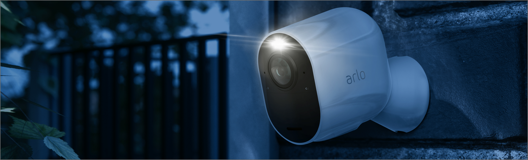 La caméra de surveillance Arlo Ultra accrochée contre un mur qui filme dans la nuit avec son projecteur intégré.