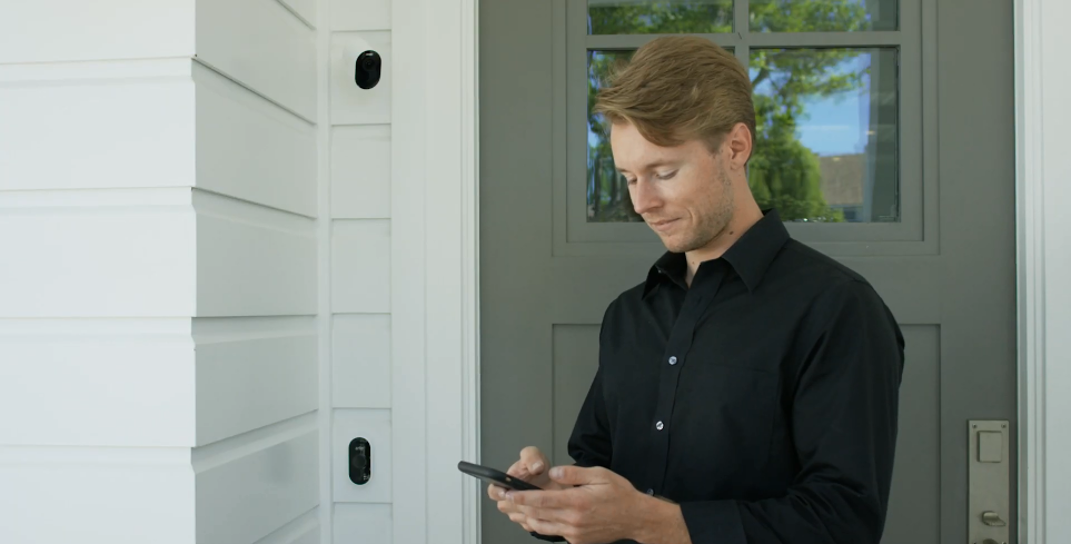 Man checking mobile phone Arlo App in front of front door following set up of Arlo Ultra