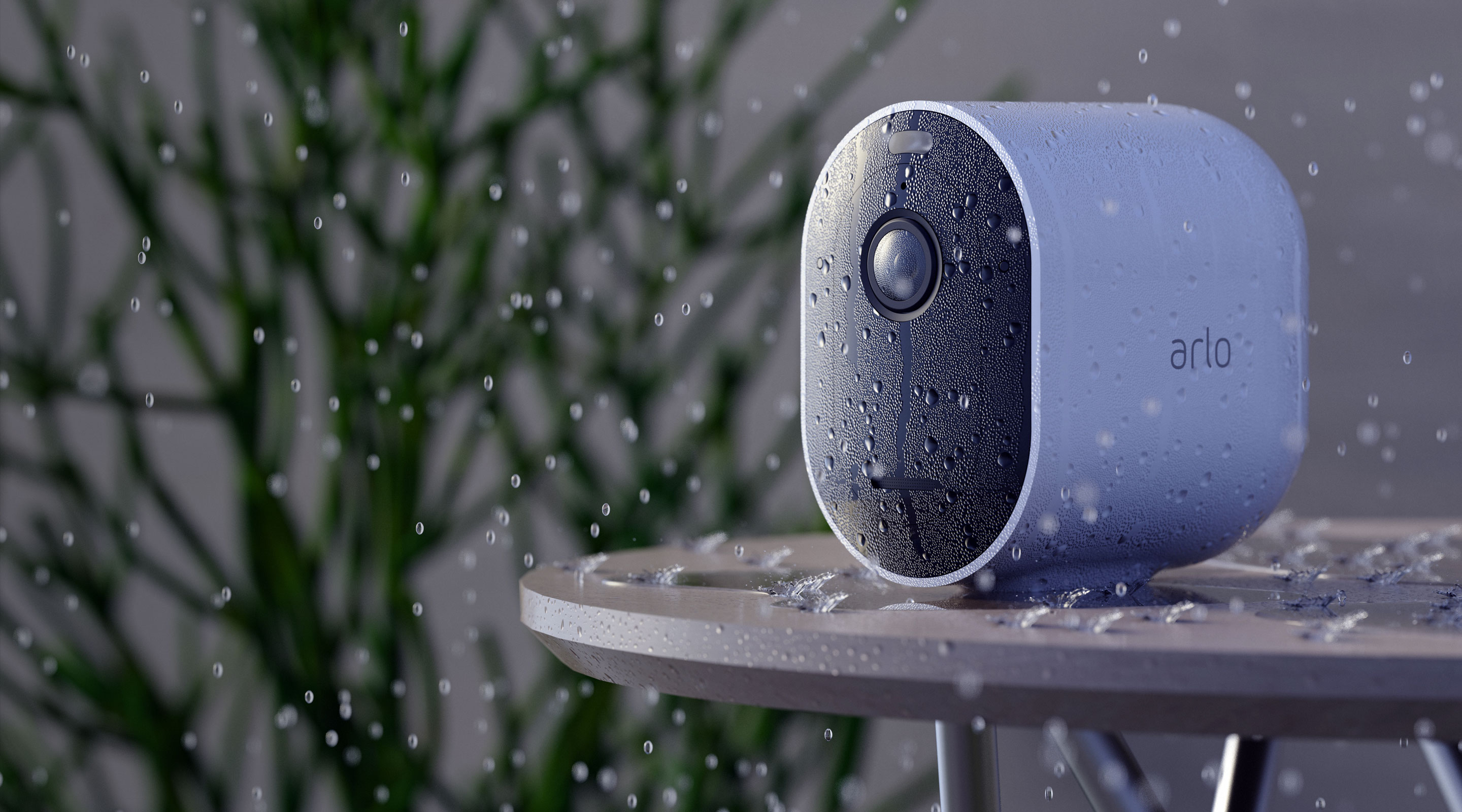 Arlo Pro 4 camera displayed on table outside in rain with water droplets