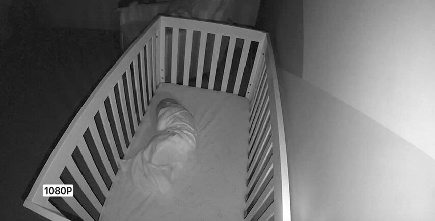 night vision view of baby in crib seen by Arlo Essential Indoor Camera